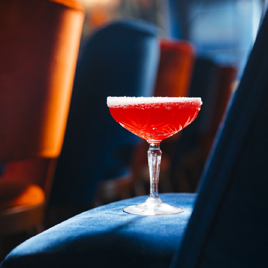 Cocktail rouge posé sur une banquette en velours bleu