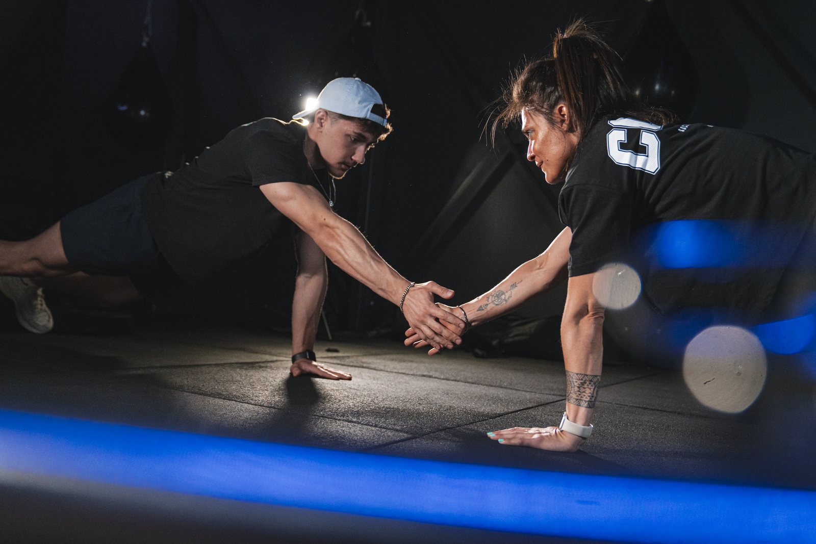 Deux sportifs en gainage se tapent dans la main, salle KeepCool