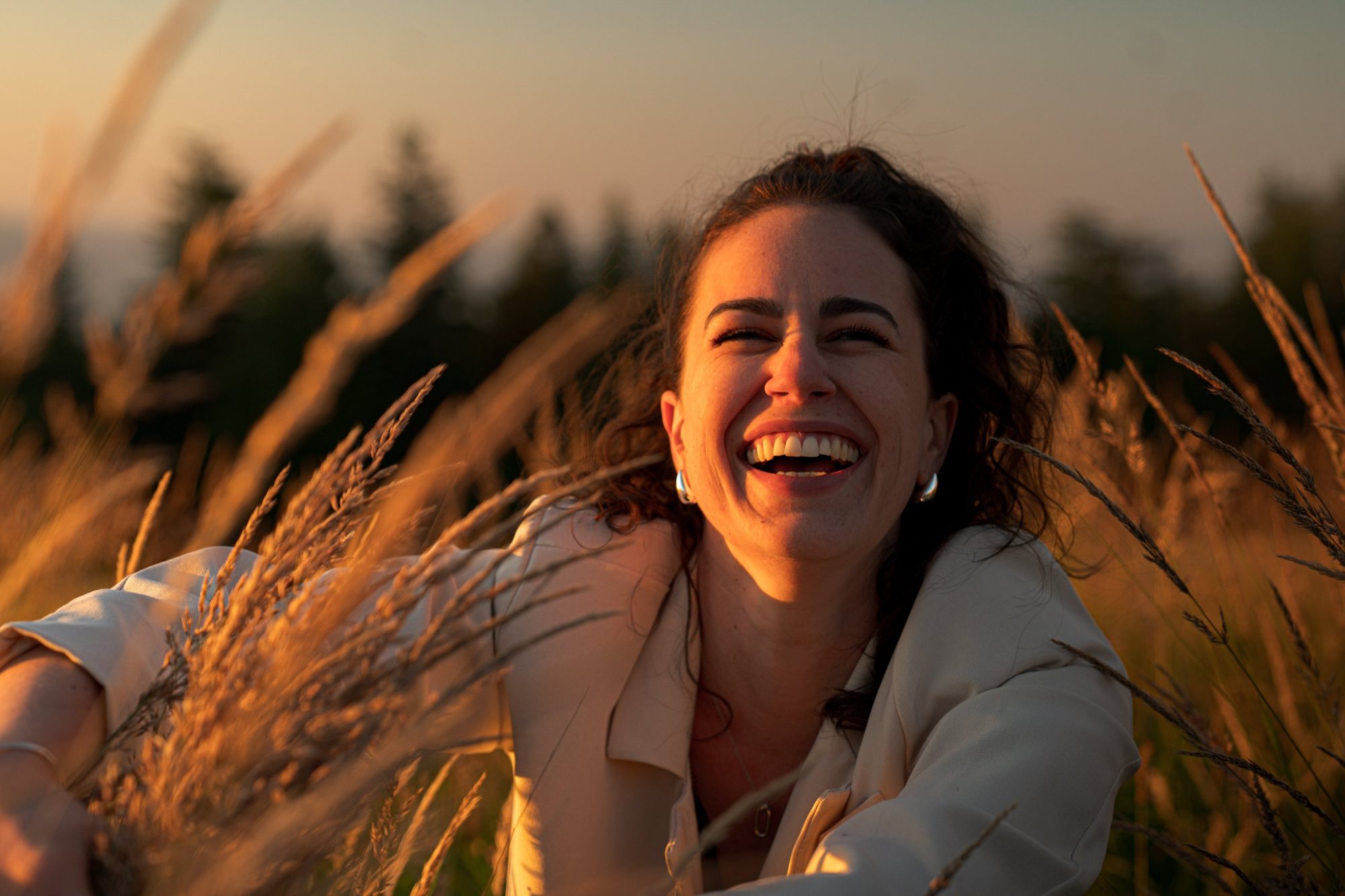 Éclat de rire dans les herbes hautes, lumière dorée, pour Les Bijoux Chics