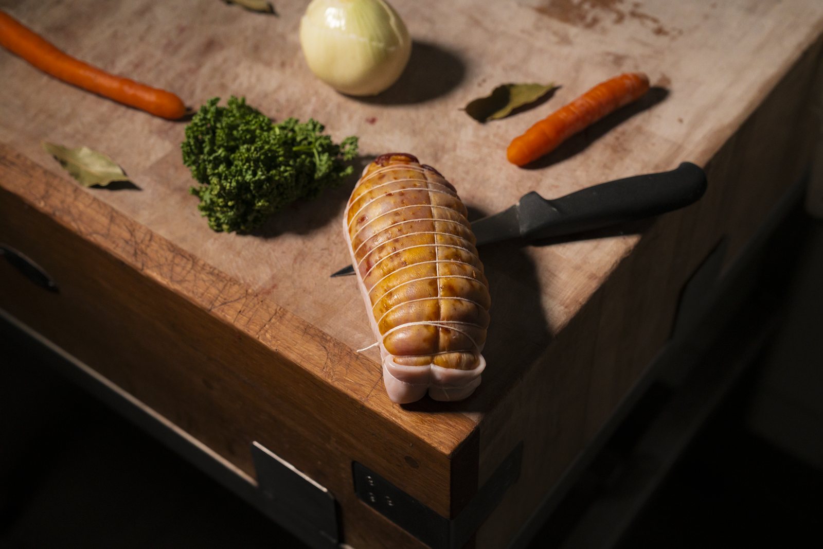 Rôti ficelé sur le billot, couteau et légumes